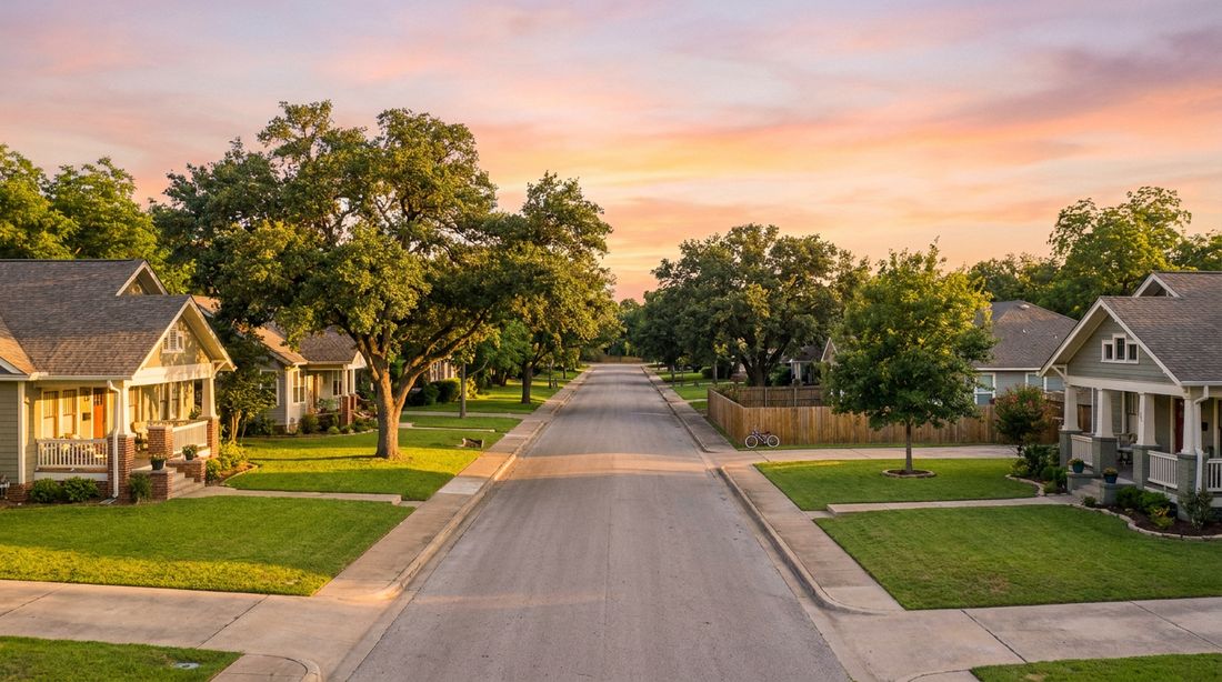 A tree-lined street of healthy front lawns at golden hour